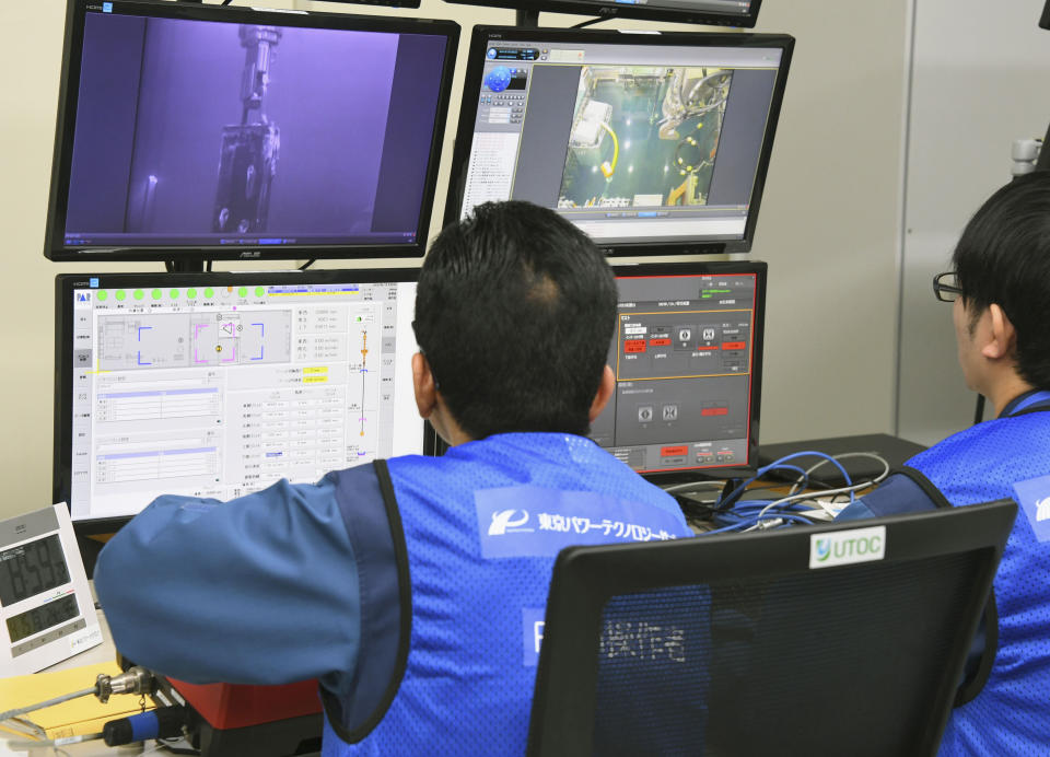Tokyo Electric Power Co. workers remotely make operation for removing fuels at Unit 3 of Fukushima Dai-ichi nuclear plant, in Okuma, Fukushima Prefecture, northeastern Japan Monday. April 15, 2019. The operator of the tsunami-wrecked nuclear plant has begun removing fuel from a cooling pool at one of three reactors that melted down in the 2011 disaster, a milestone in the decades-long process to decommission the plant. The work is carried out remotely from a control room about 500 meters (yards) away because of still-high radiation levels inside the reactor building that houses the pool. (Kyodo News via AP)
