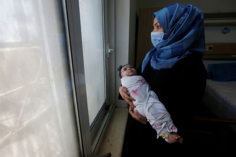 An Iraqi woman wearing a protective mask carries her baby who suffers from cancer at the Children's Hospital for Cancer Diseases in Basra