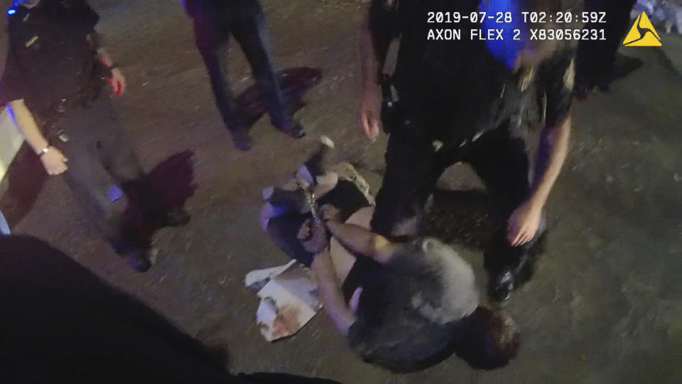 In this image from Knox County Sheriff’s Office body-camera video, cuffs on the wrists and ankles are used to restrain Johnathan Binkley in Knoxville, Tenn., on July 28, 2019. He rolled around for three more minutes, as deputies watched. One thrust a knee into his back, forcing him to be still, and he became unresponsive within a minute. Binkley’s death shows how police violate safety guidelines by restraining people in what is known as prone position. Failing to reposition people onto their sides or seated up can cause breathing or heart problems. (Knox County Sheriff’s Office via AP)