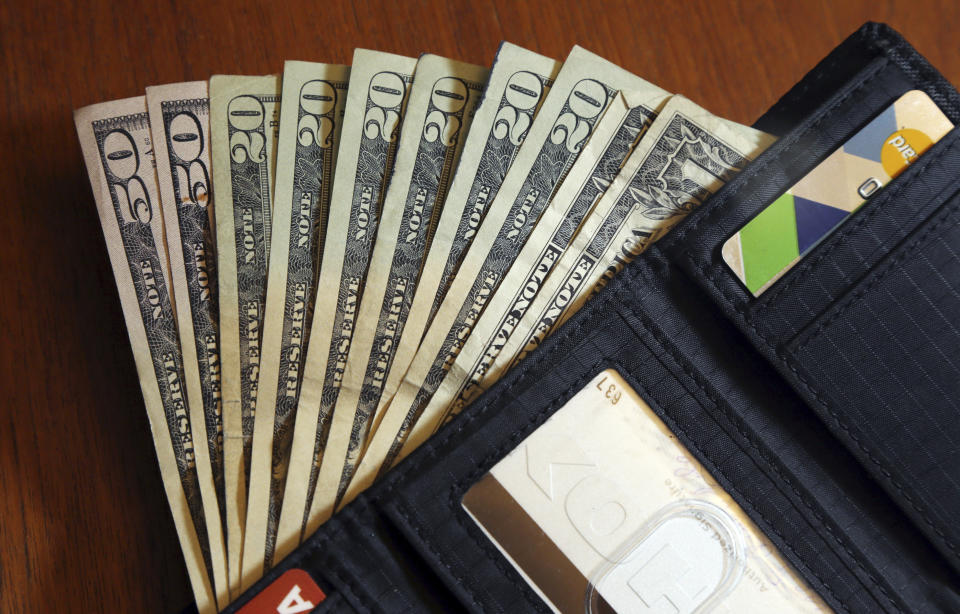 FILE - In this June 15, 2018, file photo, cash is fanned out from a wallet in North Andover, Mass. You share a lot with your spouse, but your credit score isn’t one of those things. Even if you don’t earn an income and your spouse supports you financially, it’s important to build your own credit score. Not only will your score come into play when you apply for a joint loan, but you may need to fall back on it if you ever become single again. You can build credit by using your spouse’s income on a credit card application, or by becoming an authorized user on one of their cards, and making on-time payments each month. (AP Photo/Elise Amendola, File)