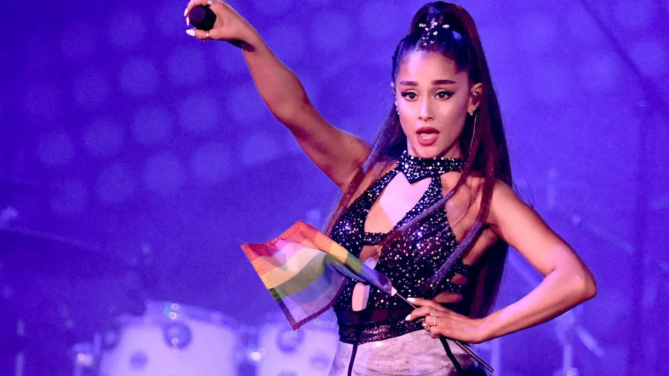 Ariana Grande holds a pride flag while performing.