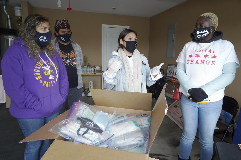 Stephanie Lopez-Burgus, Graco Hernandez Valenzuela, Maricela Tapia and Sheabria Gills, from left, stand near a box containing items being distributed by the Working Families Party, Wednesday, Dec. 16, 2020, in Lawrenceville. The party, a national progressive political movement that has endorsed the Rev. Raphael Warnock, dispatched more than a dozen organizers and several more volunteers to Georgia. (AP Photo/Tami Chappell)