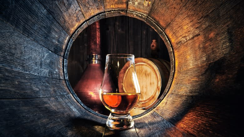 Glass of whiskey in barrel