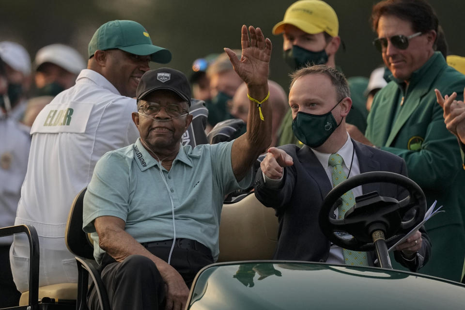 FILE - Lee Elder waves as he arrives for the ceremonial tee shots before the first round of the Masters golf tournament on Thursday, April 8, 2021, in Augusta, Ga. At far right is Phil Mickelson. Person at right in cart is unidentified. Elder broke down racial barriers as the first Black golfer to play in the Masters and paved the way for Tiger Woods and others to follow. The PGA Tour confirmed Elder’s death, which was first reported by Debert Cook of African American Golfers Digest. No cause or details were immediately available, but the tour said it spoke with Elder's family. He was 87. (AP Photo/Charlie Riedel, File)