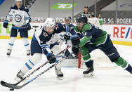 Vancouver Canucks center Zack MacEwen (71) fights for control of the puck with Winnipeg Jets defenseman Dylan DeMelo (2) during second-period NHL hockey game action in Vancouver, British Columbia, Sunday, Feb. 21, 2021. (Jonathan Hayward/The Canadian Press via AP)