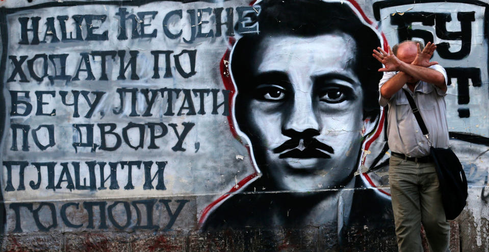 <p>A man covers his face by graffiti on a wall showing Gavrilo Princip, the Bosnian-Serb nationalist who assassinated Archduke Franz Ferdinand in 1914, in Belgrade, Serbia, Tuesday, Aug. 30, 2016. (AP Photo/Darko Vojinovic) </p>