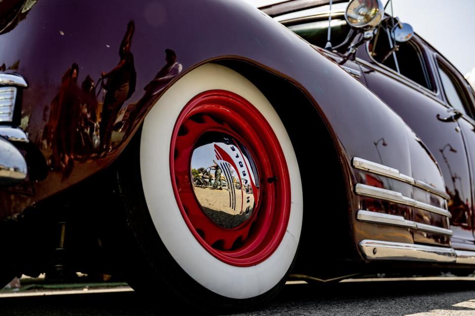 Closeup of a whitewall tire with chrome that reflects passersby.