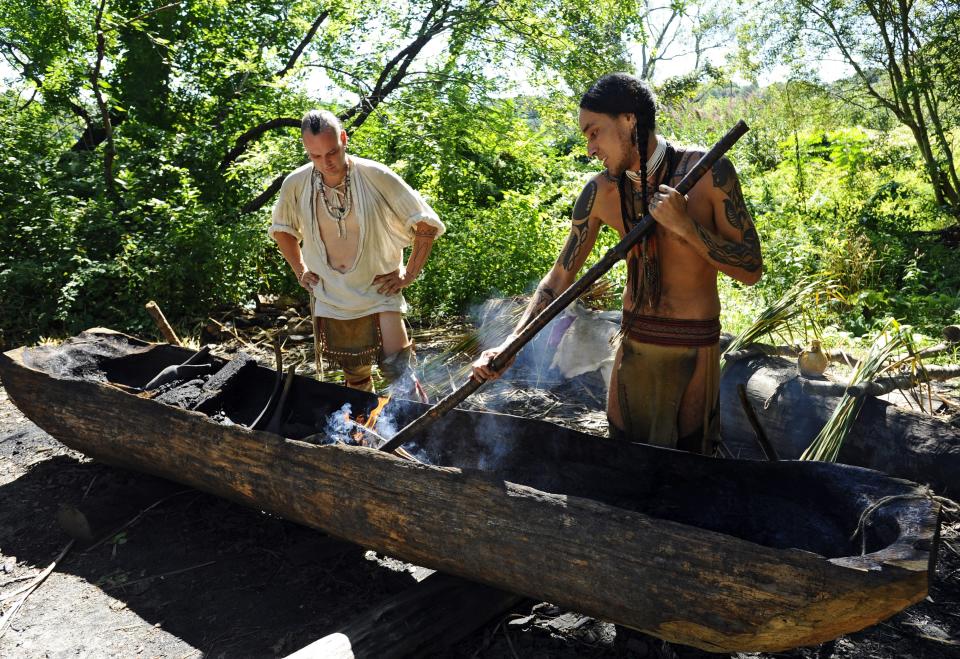 Mashpee Wampanoag and Plimoth Patuxet site supervisor Phillip Wynne, RIGHT, scrapes out a pine mishoon while Dan Shears observes. Plimoth Patuxet is a living museum that has a replica 17-century Pilgrim village and Wampanoag settlement.