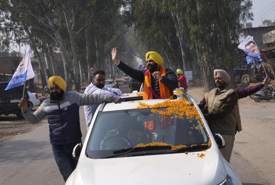 Aam Aadmi Party's candidate Harbhajan Singh from the Jandiala constituency, atop a car, campaigns for assembly elections on the outskirts of Amritsar, in Indian state of Punjab, Tuesday, Feb. 15, 2022. India's Punjab state will cast ballots on Sunday that will reflect whether Indian Prime Minister Narendra Modi's ruling Bharatiya Janata Party has been able to neutralize the resentment of Sikh farmers by repealing the contentious farm laws that led to year-long protests. (AP Photo/Manish Swarup)