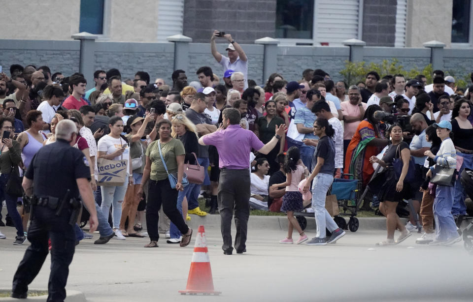 FILE - People gather across the street from a shopping center after a shooting Saturday, May 6, 2023, in Allen, Texas. A 33-year-old man with an arsenal of legally-purchased firearms killed eight people and wounded seven others at a Dallas-area shopping center. He had posted online about his white supremacist and misogynistic views. A police officer fatally shot him within four minutes. (AP Photo/LM Otero, File)