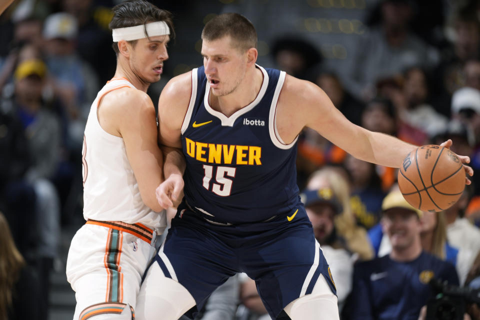 Denver Nuggets center Nikola Jokic, right, posts up against San Antonio Spurs forward Zach Collins, left, in the first half of an NBA basketball game Sunday, Nov. 26, 2023, in Denver. (AP Photo/David Zalubowski)