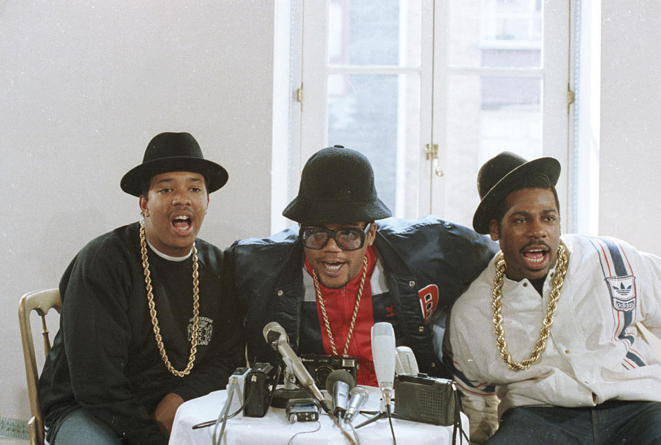 ARCHIVO - El grupo de rap RUN D.M.C., de visita en Londres para dos conciertos, durante una conferencia de prensa. De izquierda a derecha Joseph Simmons, Darryl McDaniels, y Jason Mizell. Cuando los ejecutivos de Adidas vieron al grupo pedir a los fanáticos que presumieran sus tenis de la marca y miles se quitaron los zapatos y los agitaron en el aire en una actuación en el Madison Square Garden, firmaron un trato de 1 millón de dólares que resultó en su propia línea de zapatos en 1988. (Foto AP/Peter Kemp, archivo)