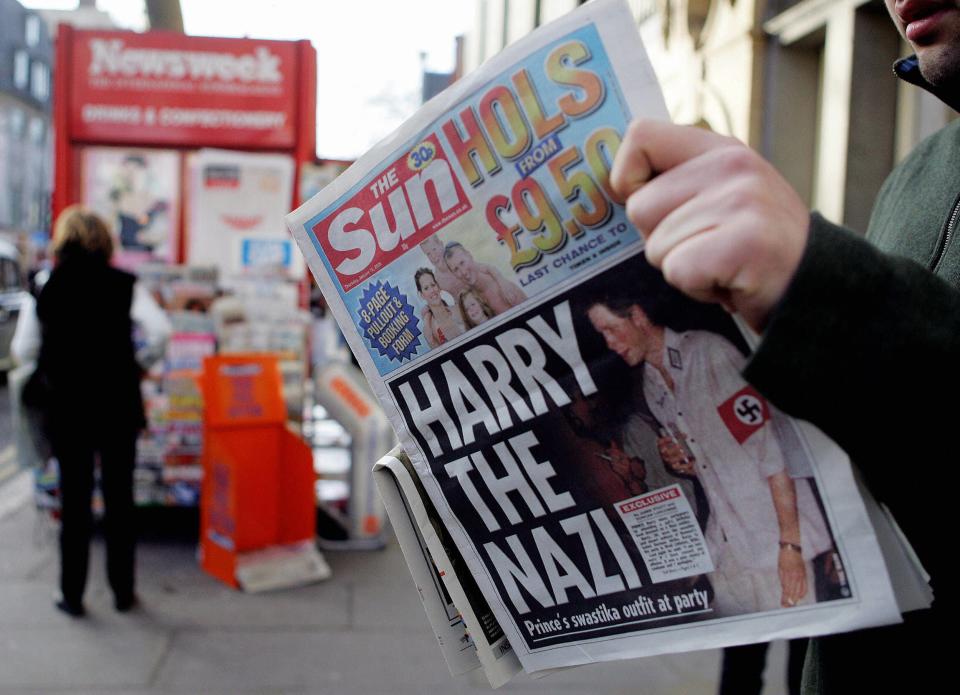 A man reads The Sun newspaper in London 13 January, 2005, with a headline about Prince Harry wearing a Nazi uniform at a costume party.