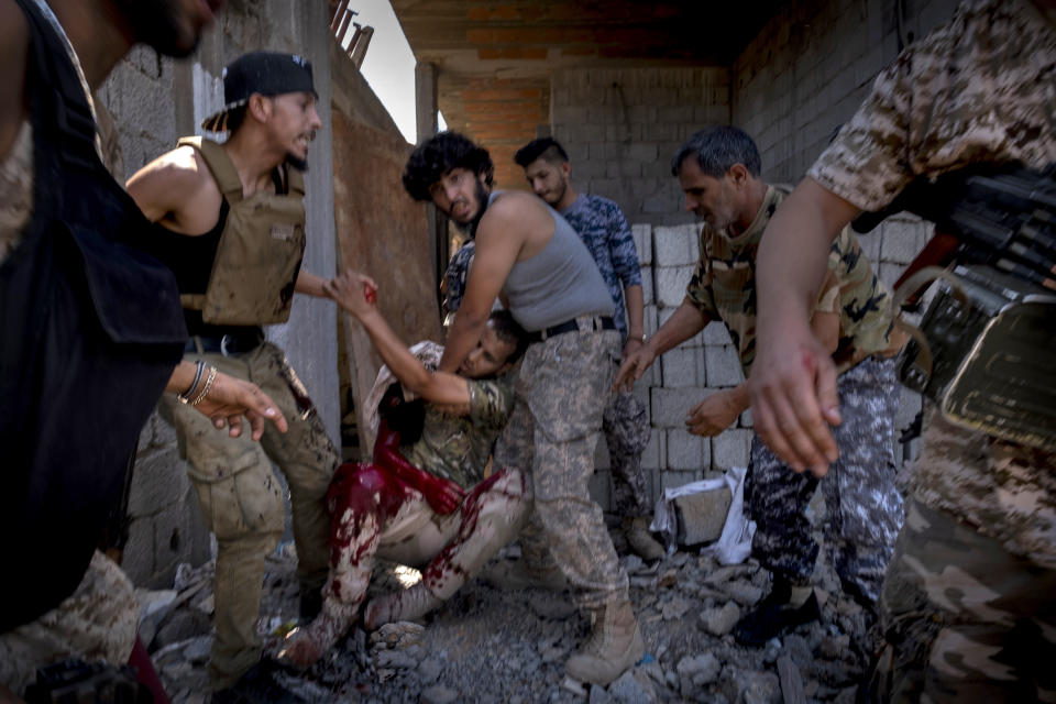 File - In this Saturday Sept. 7, 2019 photo, a mortally wounded fighter of the 'Shelba' unit, allied with the U.N.-supported Libyan government, is moved by comrades after being shot at the Salah-addin neighborhood front line in Tripoli, The US is making efforts to convince power brokers in Libya and Sudan to expel the Russian private military company Wagner, regional officials tell The Associated Press. The pressure comes after Washington expanded sanctions on the group. Wagner has played a role in Libya's conflict but has also been linked with a powerful Sudanese paramilitary. (AP Photo/Ricard Garcia Vilanova, File)