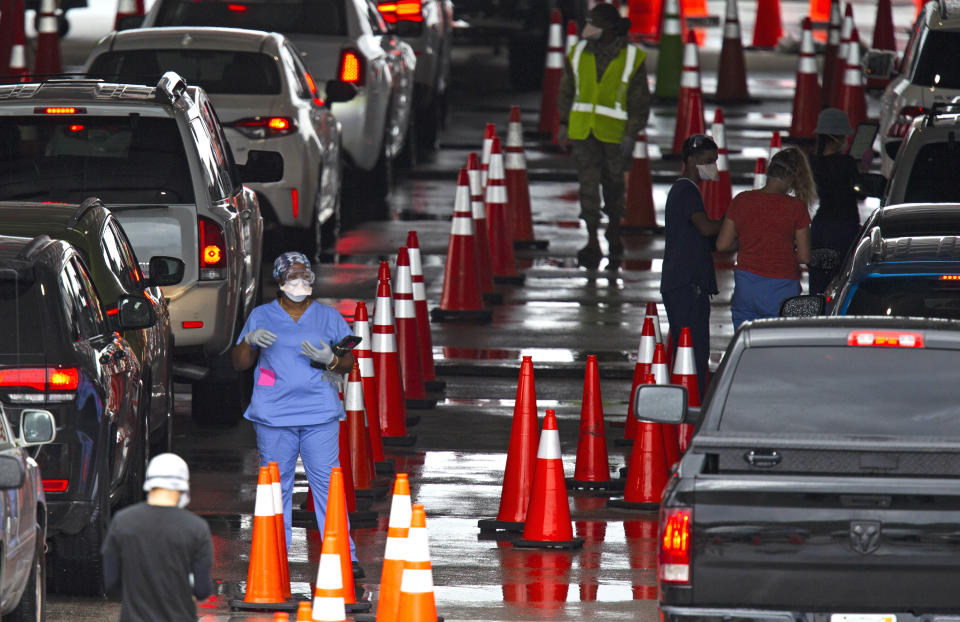 Vehicles line up as healthcare workers help to check-in as citizens are being tested at the COVID-19 drive-thru testing center at Hard Rock Stadium in Miami Gardens on Sunday, Nov. 22, 2020. (David Santiago/Miami Herald via AP)