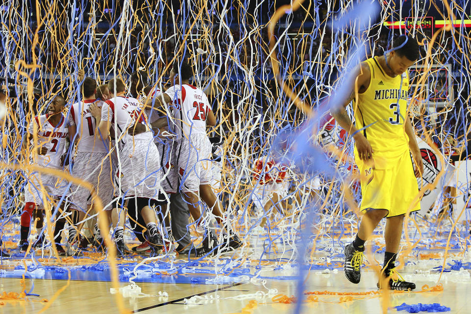 FILE - In this April 8, 2013, file photo, Michigan guard Trey Burke (3) walks off the court as confetti falls on Louisville players, including Russ Smith (2), Luke Hancock (11), Stephan Van Treese (44) and Zach Price (25), after the NCAA Final Four tournament college basketball championship game in Atlanta. The Final Four teams would've been in Atlanta, Friday, April 3, 2020, getting in their final practices for Saturday's semifinal games. (Curtis Compton/Atlanta Journal-Constitution via AP, File)