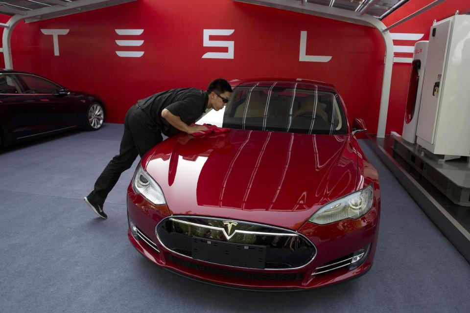 A worker cleans a Tesla Model S sedan before a event to deliver the first set of cars to customers in Beijing, China, Tuesday, April 22, 2014. Tesla Motors delivered its first eight electric sedans to customers in China on Tuesday and CEO Elon Musk said the company will build a nationwide network of charging stations and service centers as fast as it can. (AP Photo/Ng Han Guan)
