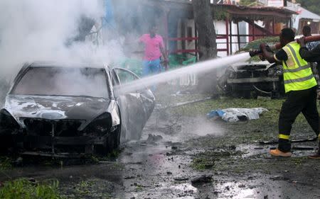 A firefighter attempts to extinguish a burning vehicle at the scene of an attack where a car laden with explosives rammed into a cafeteria in Somalia's capital Mogadishu, May 8, 2017. REUTERS/Feisal Omar