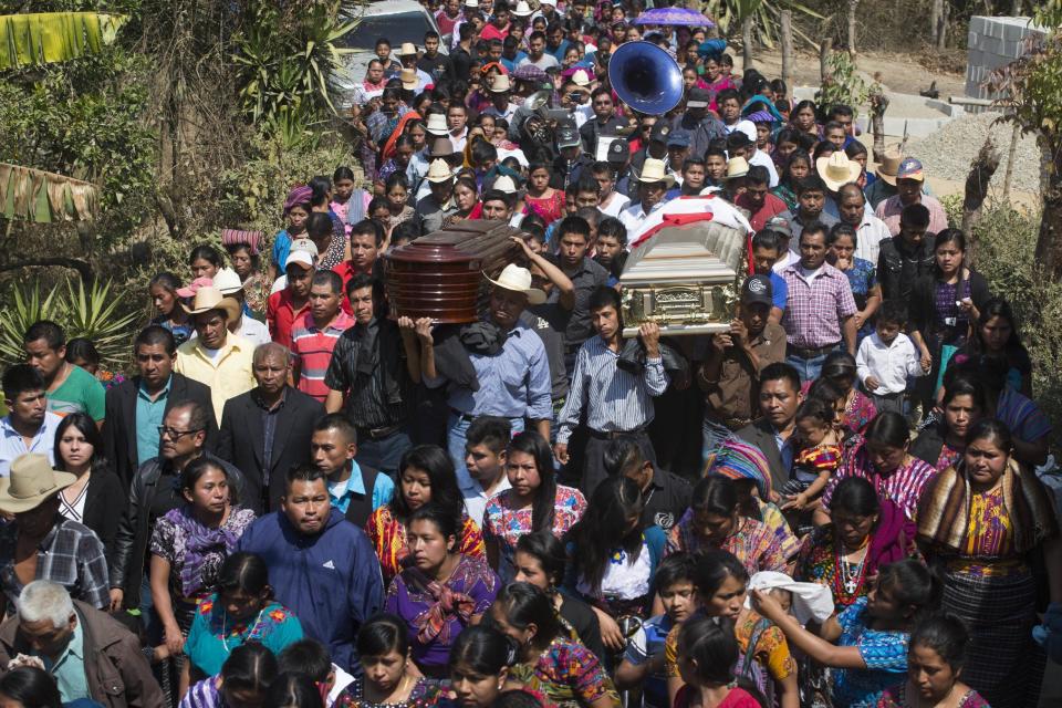 Thousands accompany the coffins containing the remains of two children, who were kidnapped and then killed over the weekend when family could not raise the ransom money, in a funeral procession in Ajuix, Guatemala, Tuesday, Feb. 14, 2017. Authorities found the bodies of the two boys, aged 10 and 11, on Sunday, stabbed and thrown into sacks in the municipality of San Juan Sacatepéquez, northwest Guatemala. (AP Photo/Moises Castillo)