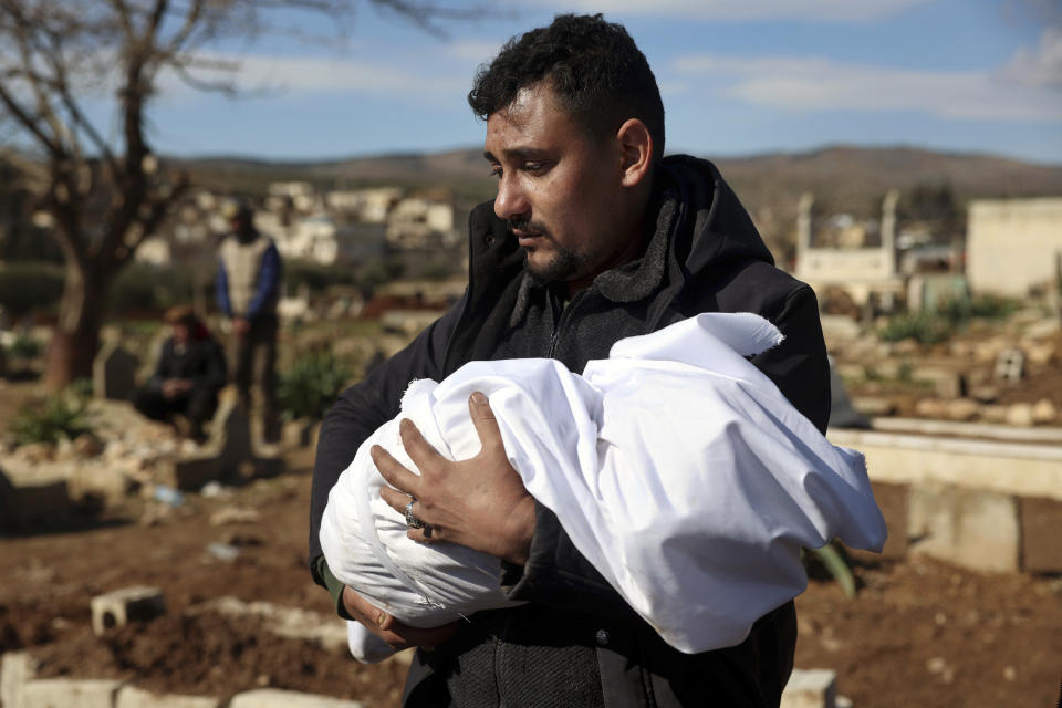 A man carries the body of a family member who died in a devastating earthquake that rocked Syria and Turkey at a cemetery in the town of Jinderis, Aleppo province, Syria, Tuesday, Feb. 7, 2023. A newborn girl was found buried under debris with her umbilical cord still connected to her mother, Afraa Abu Hadiya, who was found dead, according to relatives and a doctor. The baby was the only member of her family to survive from the building collapse Monday in Jinderis, next to the Turkish border, Ramadan Sleiman, a relative, told The Associated Press. (AP Photo/Ghaith Alsayed)