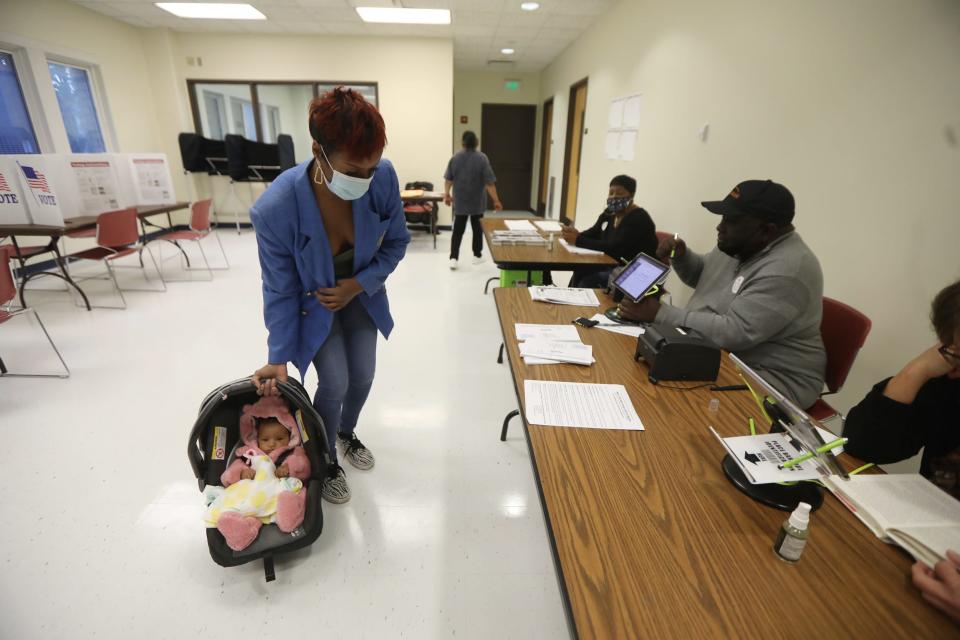 Brookelynne Young puts down her 4-month-old daughter, Tyme Cohen, as she checks in to work the election at Wilson Academy on Genesee Street in Rochester on Nov. 2, 2021.
