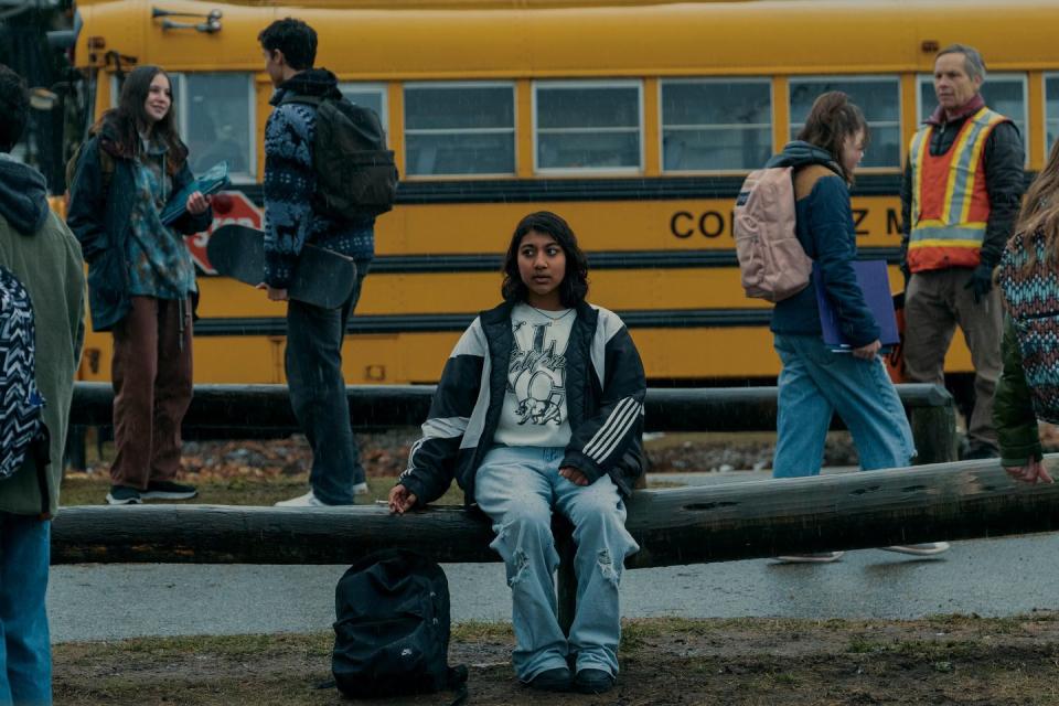 a person sitting on a bench in front of a yellow school bus