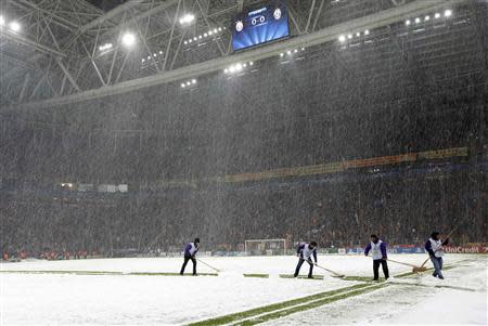 Workers rush to clean the snow from the pitch after the Champions League soccer match between Galatasaray and Juventus was paused for 20 minutes due heavy snowfall in Istanbul December 10, 2013. REUTERS/Murad Sezer