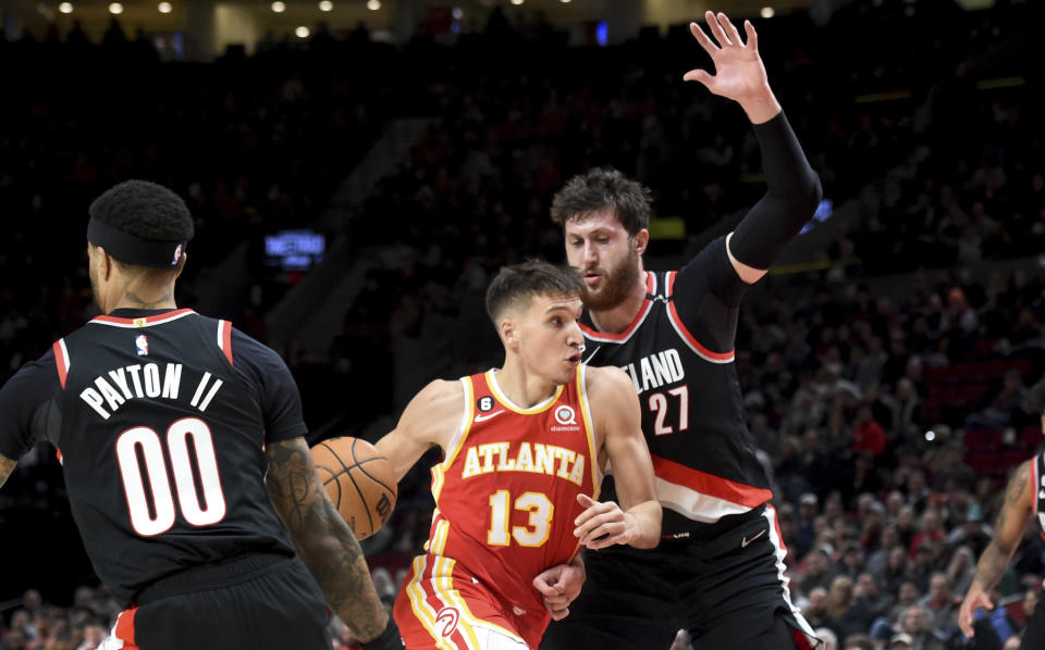 Atlanta Hawks guard Bogdan Bogdanovic, center, drives to the basket past Portland Trail Blazers guard Gary Payton II, left, and center Jusuf Nurkic, right, during the first half of an NBA basketball game in Portland, Ore., Monday, Jan. 30, 2023. (AP Photo/Steve Dykes)
