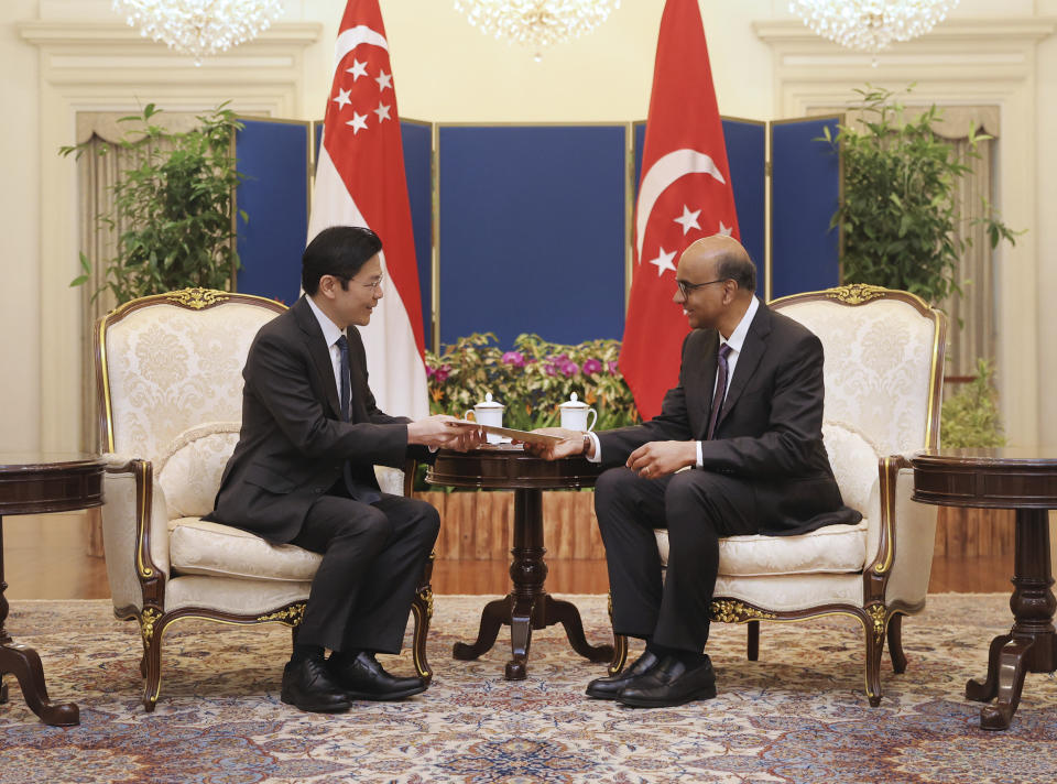 In this photo released by Singapore's Ministry of Communications and Information, Singapore President Tharman Shanmugaratnam, right, talks with Singapore's Deputy Prime Minister Lawrence Wong at the Istana in Singapore, Monday, May 13, 2024. (Mohd Fyrol/Ministry of Communications and Information via AP)