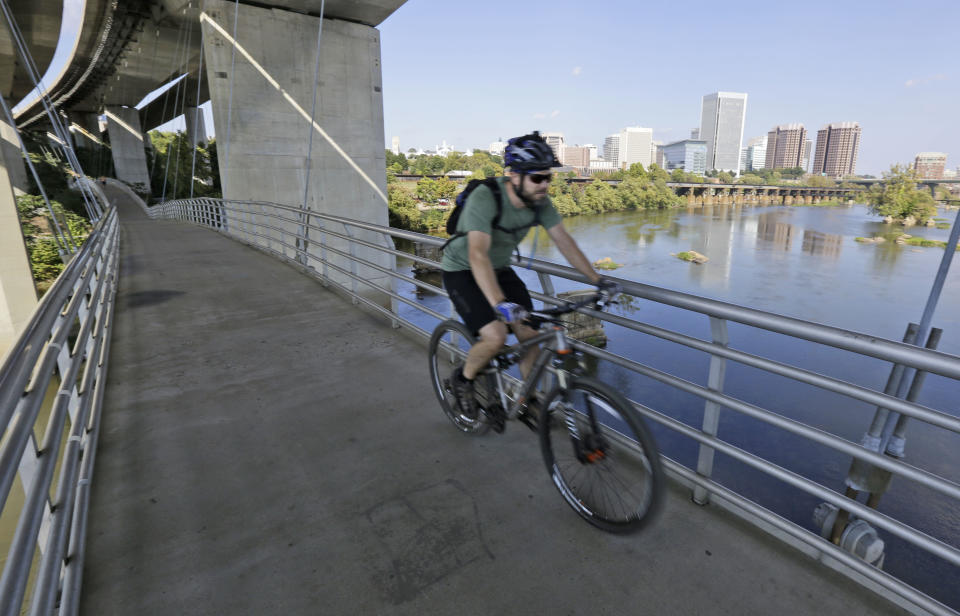 This Oct. 1, 2013 photo shows a bicyclist riding on a bridge suspended under the Lee Bridge over the James river to Belle Isle, in Richmond, Va., where you’ll find locals exploring the 54-acre island and resting on its rocky shores. (AP Photo/Steve Helber)