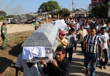 Family members and friends carry coffins during the funeral of people who were killed after a military helicopter, carrying Mexico's interior minister and the governor of the southern state of Oaxaca, crashed on top of two vans in an open field while trying to land in Santiago Jamiltepec, Mexico February 17, 2018. REUTERS/Jorge Luis Plata