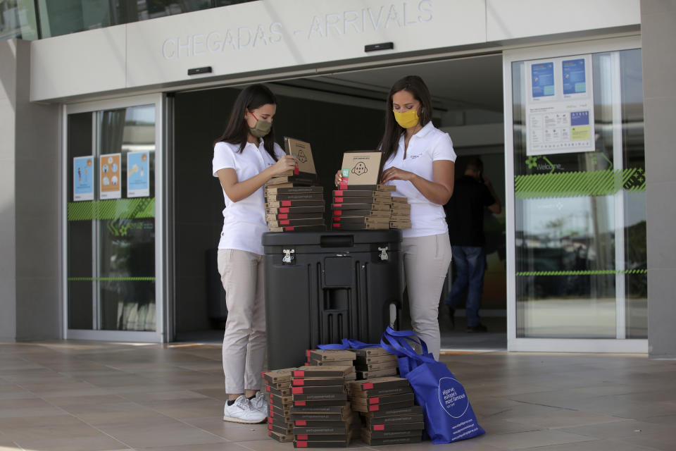 A Algarve tourism authority workers prepare COVID-19 welcome kits containing masks and disinfectant to hand out to passengers arriving at Faro airport, outside Faro, in Portugal's southern Algarve region, Monday, May 17, 2021. British vacationers began arriving in large numbers in southern Portugal on Monday for the first time in more than a year, after governments in the two countries eased their COVID-19 pandemic travel restrictions. (AP Photo/Ana Brigida)