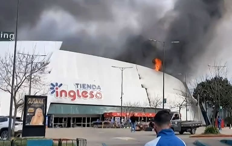 Esta captura de un vídeo de AFP muestra las llamas y el humo negro de un incendio que se eleva desde el principal centro comercial de Punta del Este, departamento de Maldonado, Uruguay, el 7 de agosto de 2022.