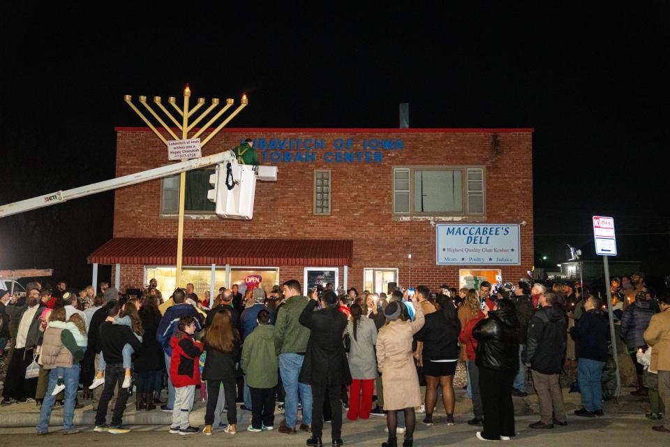 More than 100 people gather as they celebrate the lighting of the menorah Thursday outside Maccabee's Deli in Des Moines.