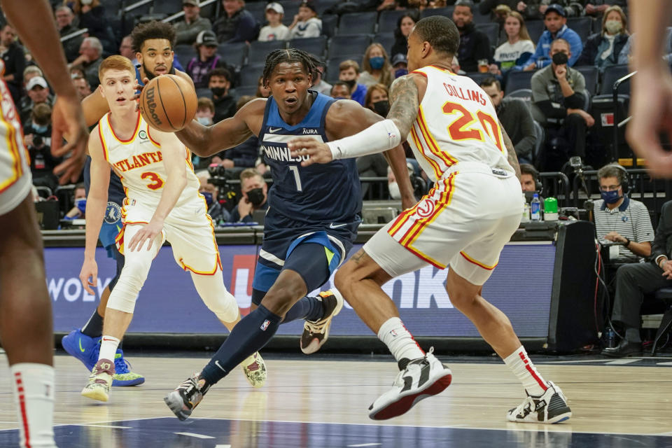 Minnesota Timberwolves guard Anthony Edwards (1) drives past Atlanta Hawks forward John Collins, right, as Hawks forward Kevin Huerter (3) looks on during the first half of an NBA basketball game Monday, Dec. 6, 2021, in Minneapolis. (AP Photo/Craig Lassig)