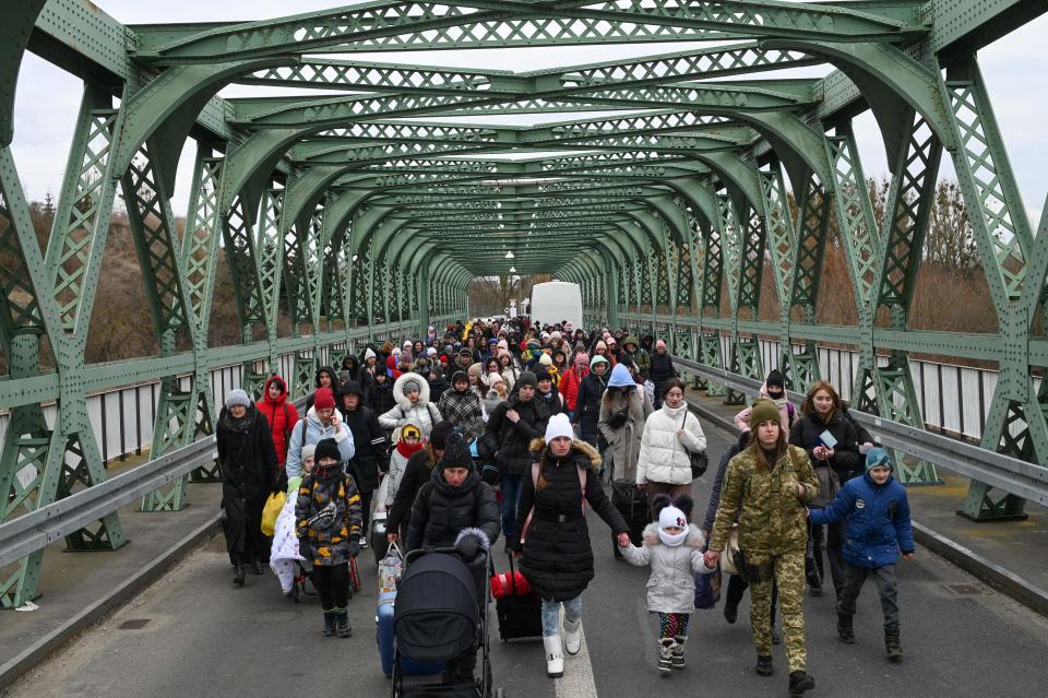 Ukrainian refugees walk on a bridge at the buffer zone with the border with Poland in western Ukraine.