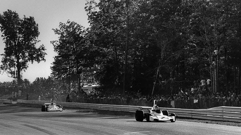 A black and white photo of F1 cars racing at Watkins Glen International. 