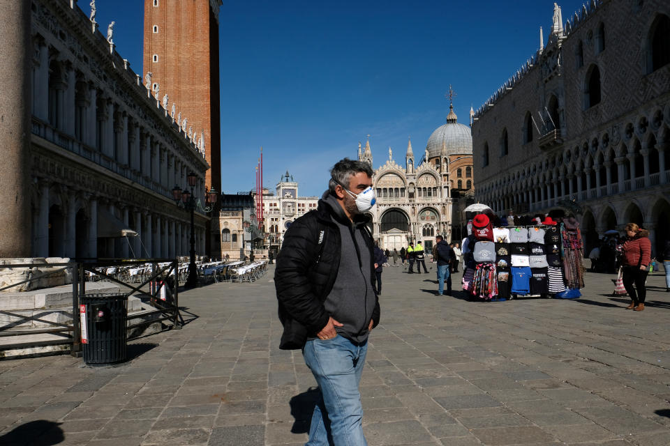 A man wearing a protective mask walks through an empty Saint Mark's Square in Venice as Italy battles a coronavirus outbreak, Venice, Italy, February 27, 2020. REUTERS/Manuel Silvestri