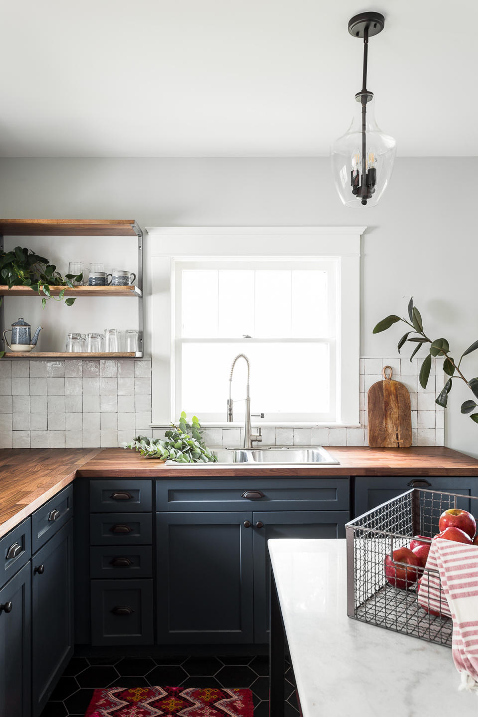 A kitchen with dark flooring and red rug