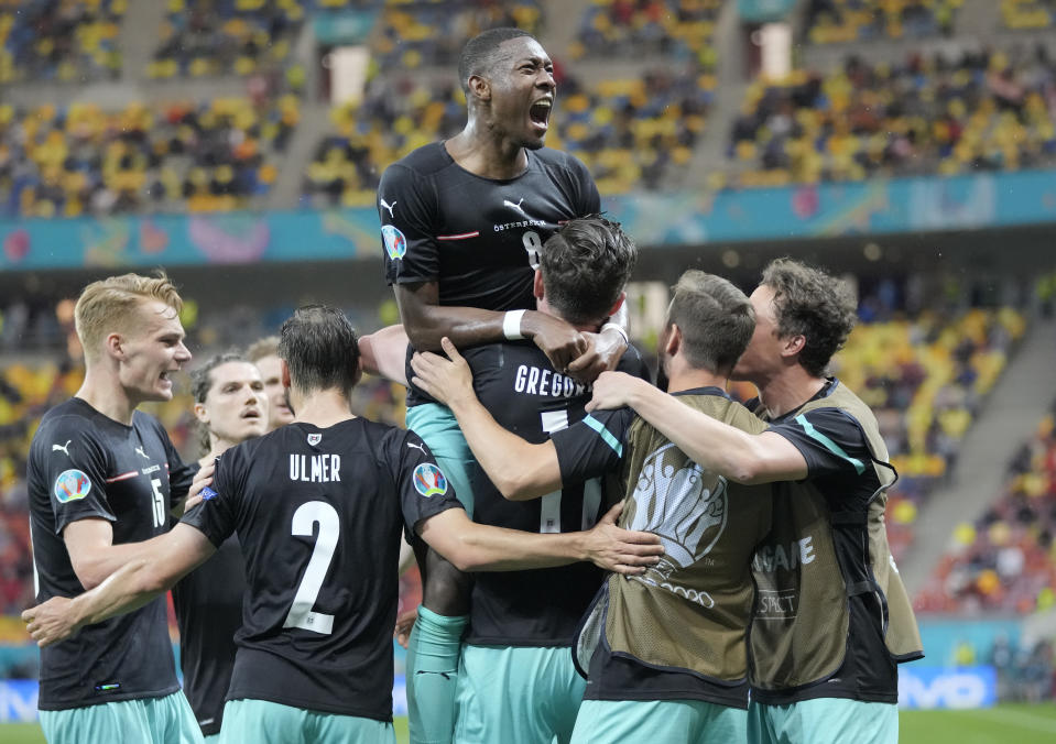 Austria's Michael Gregoritsch, center down, celebrates with teammates after scoring his side's second goal during the Euro 2020 soccer championship group C match between Austria and Northern Macedonia at the National Arena stadium in Bucharest, Romania, Sunday, June 13, 2021. (AP Photo/Vadim Ghirda, Pool)