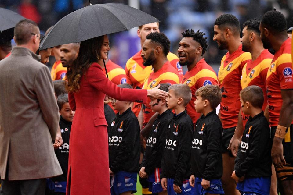 Britain's Catherine, Princess of Wales shelters from the rain under an umbrella as she meet the Papua New Guinea players before the 2021 rugby league World Cup men's Quarter Final match between England and Papua New Guinea at DW Stadium in Wigan in north-west England on November 5, 2022. (Photo by Oli SCARFF / AFP) (Photo by OLI SCARFF/AFP /AFP via Getty Images)