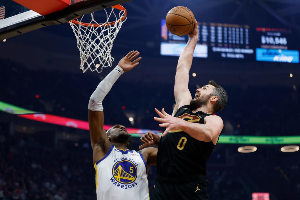 Cleveland Cavaliers forward Kevin Love (0) shoots against Golden State Warriors forward Kevon Looney (5) during the first half of an NBA basketball game Friday, Jan. 20, 2023, in Cleveland. (AP Photo/Ron Schwane)