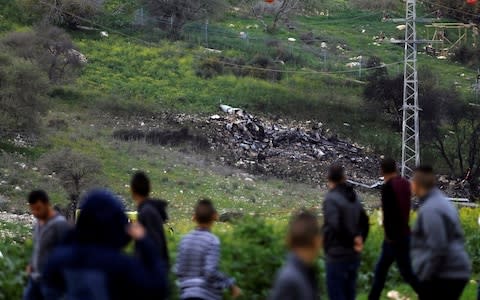 Bystanders look at the remains of an F-16 Israeli war plane near the village of Harduf, Israel  - Credit: Reuters