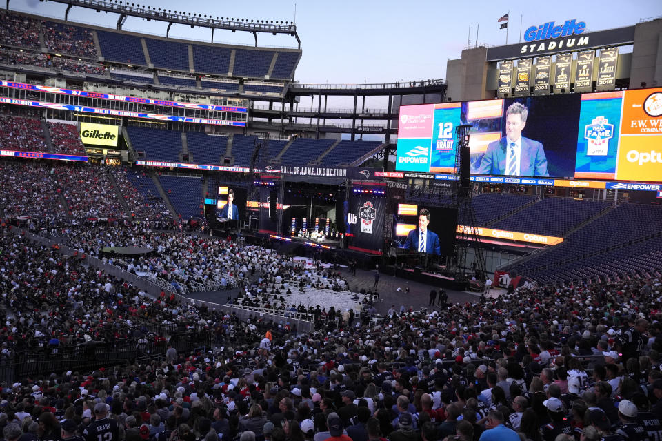 Former New England Patriots quarterback Tom Brady appears on large screens while speaking from the stage during Patriots Hall of Fame induction ceremonies for Brady at Gillette Stadium, Wednesday, June 12, 2024, in Foxborough, Mass. (AP Photo/Steven Senne)