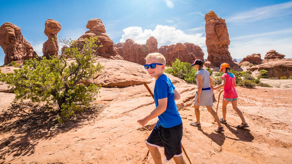 happy family hiking together in the beautiful rock formations of Arches National Park.