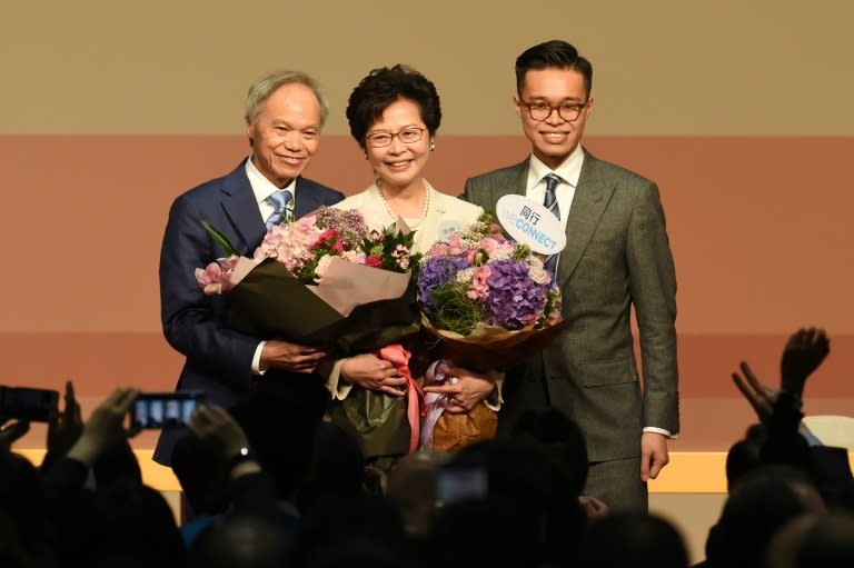 Hong Kong's new chief executive Carrie Lam (C) has pledged to mend political rifts after winning a vote dismissed as a sham by democracy activists