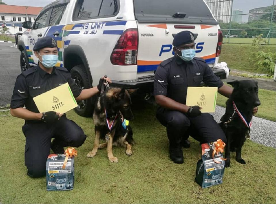 Johor police contingent K9 unit dog Barny and his handler Lance Corporal Calvin Maluni (left) with Mailo and his handler Lance Corporal K. Thiru (right) after being presented with their awards at the Johor police contingent headquarters in Johor Baru today. ― Picture by Ben Tan