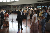 An airport employee directs people for check-in for a British Airways flight to Heathrow airport, Friday Aug.14, 2020 at Nice airport, southern France. British holidaymakers in France were mulling whether to return home early Friday to avoid having to self-isolate for 14 days following the U.K. government's decision to reimpose quarantine restrictions on France amid a recent pick-up in coronavirus infections. (AP Photo/Daniel Cole)