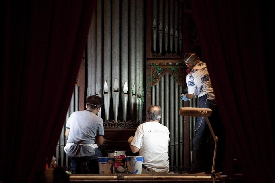 William Adair of Gold Leaf Studios, center, works with his staff to remove green paint from the organ in the Washington National Cathedral's historic Bethlehem Chapel, Tuesday, July 30, 2013, in Washington. Officials at the cathedral discovered the paint inside two chapels Monday afternoon. The paint was splashed onto the organ and on the floor inside the Bethlehem Chapel on the basement level and inside Children's Chapel in the nave of the cathedral. (AP Photo/Carolyn Kaster)