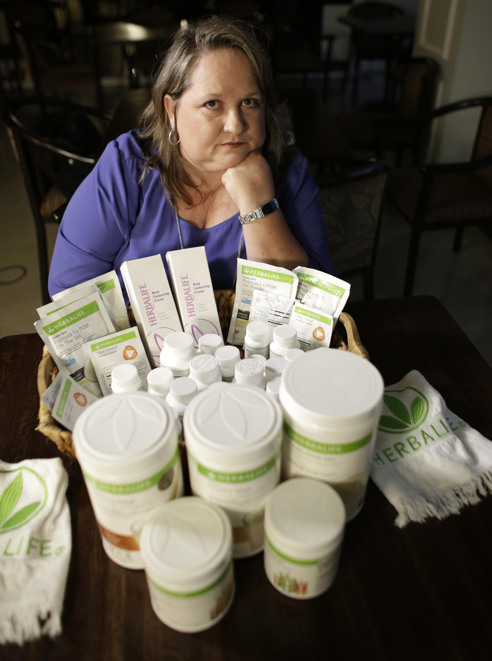 In this Nov. 14, 2017, photo, Patricia Rodgers poses with Herbalife products in Hallandale Beach, Fla. Rodgers and others are suing the multi-level marketing company that sells its products through a network of distributors who recruit more distributors. Los Angeles-based Herbalife, a publicly traded company with 2017 net sales of $4.4 billion, has long been embroiled in litigation and regulatory actions over its business practices, which have been compared by some to a pyramid scheme. (AP Photo/Lynne Sladky)